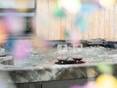 A hot tub with two glasses of red wine at Cae Pren in New Mills near Llanfair Caereinion