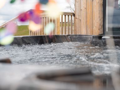 A bubbling hot tub on a wooden deck outside at Cae Pren in New Mills near Llanfair Caereinion