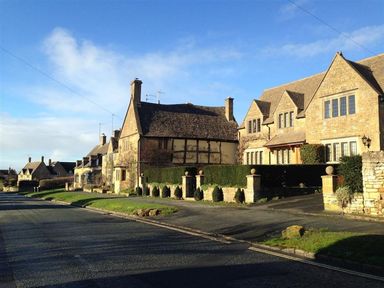 A street view with stone houses and a hedge along the sidewalk at Broadway Cottage in Broadway