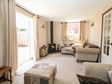 A living room with armchairs a wood burner and curtains at The Old Chapel in Foxley near Bawdeswell
