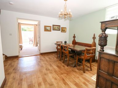 A dining room with wooden table and chairs three paintings on wall and a chandelier at The Old Chapel in Foxley near Bawdeswell
