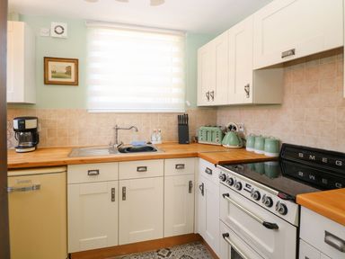 A kitchen with white cabinets wooden countertops a stove a sink and small appliances at The Old Chapel in Foxley near Bawdeswell