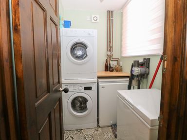A utility room with a stacked washer and dryer a freezer and cleaning tools at The Old Chapel in Foxley near Bawdeswell