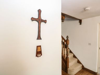 A wooden cross and holy water font on a wall near a staircase at The Old Chapel in Foxley near Bawdeswell