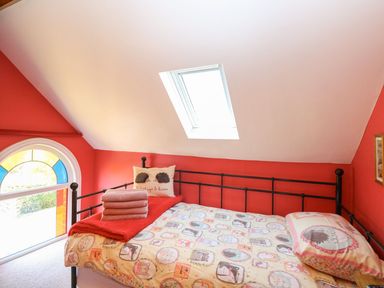 A bedroom with a bed that has animal print bedding towels on the bed a skylight window and a large arched window at The Old Chapel Foxley near Bawdeswell