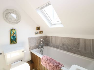 A bathroom with a toilet bathtub and skylight at The Old Chapel in Foxley near Bawdeswell