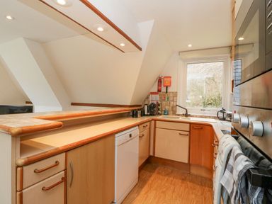 A kitchen with wooden cabinets a dishwasher a sink under a window and built in oven at Lodge 2 - Inglewood Lodge in Spean Bridge