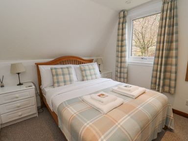 A bedroom with a double bed two bedside tables lamps and a window at Lodge 2 - Inglewood Lodge Spean Bridge