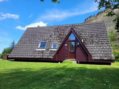 A triangular shaped house with two skylights on the roof and a door in the middle on grass at Lodge 2 - Inglewood Lodge in Spean Bridge