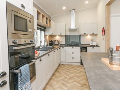A kitchen with white cabinets stainless steel appliances and a countertop with a wine cooler at 18 Manleigh Park in Combe Martin