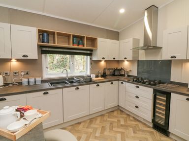 A kitchen with white cabinets a gas stove a wine cooler and a window above the sink at 18 Manleigh Park in Combe Martin
