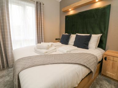 A bedroom with a made bed with towels and cushions at 18 Manleigh Park in Combe Martin