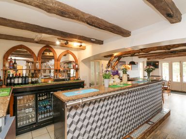 A bar area with bottles and glasses behind the counter and a patterned front at 18 Manleigh Park in Combe Martin