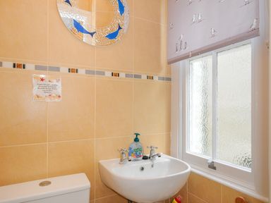 A bathroom with a sink and a toilet under a window with a seagull patterned blind at Sea Pinks in Looe