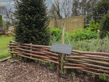 A garden area with wooden fencing and a sign saying glad you made it burland 2 at Burr 2 Shepherds Hut Swimbridge near Barnstaple