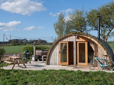 An outdoor glamping pod with a picnic table grill hot tub and bicycle at Glamping Pod 1 Comfort in Lebberston