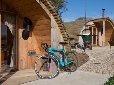 A wooden pod with a blue bicycle leaning against it and a green grill on a patio at Glamping Pod 1 Comfort in Lebberston