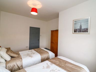 A bedroom with two single beds a wooden wardrobe a gray door and a framed picture on the wall at No 1 Lodge Wood in Kenmare County Kerry