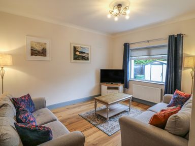 A living room with a television and seating at No 1 Lodge Wood, Kenmare, County Kerry