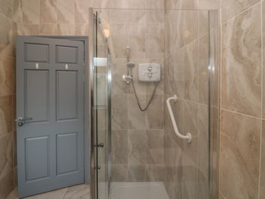 A shower stall with glass door and gray door at No 1 Lodge Wood, Kenmare, County Kerry