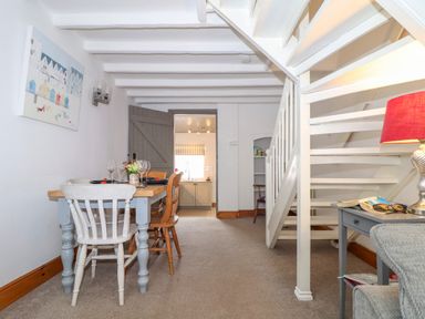 A dining area with a table and chairs next to a staircase in a living space at Cobblestone Cottage in Bude