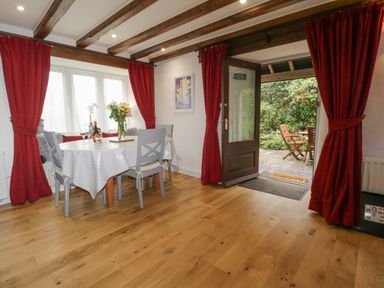 A dining area with a table and chairs next to a glass door leading to a garden at 4 Barton Cottages Down Thomas near Plymouth