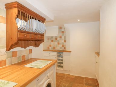 A kitchen with wooden countertops tiled backsplash and plate rack at 4 Barton Cottages Down Thomas near Plymouth