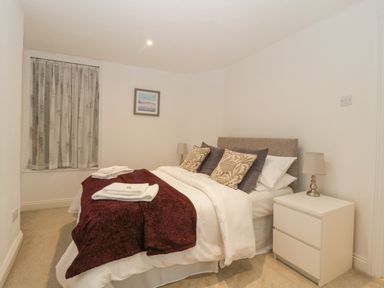 A bedroom with a double bed a bedside table with a lamp a window with curtains and a picture on the wall at 4 Barton Cottages in Down Thomas near Plymouth