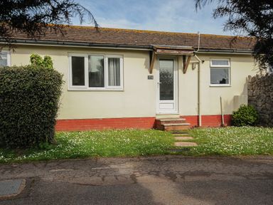 A bungalow with a front door window and small garden at Chalet 2 at Landscove Holiday Park in Brixham