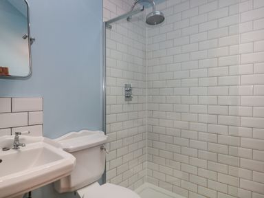 A bathroom with a sink toilet and a glass shower enclosure with white tile at The Cart Shed in Barwick near Yeovil Somerset