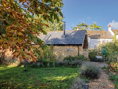 A building with a sloped roof and chimney in a garden at The Cart Shed in Barwick near Yeovil, Somerset