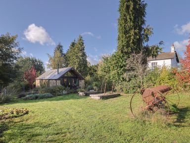 A garden with a shed, trees, and flower beds at The Cart Shed, Barwick near Yeovil, Somerset