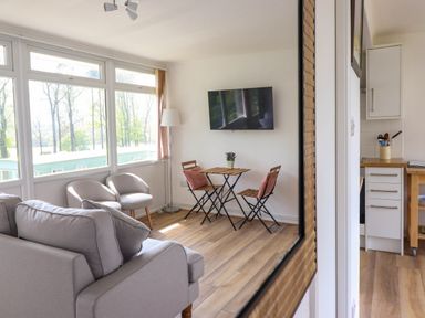 A living room with two armchairs a small table with two chairs and a wall-mounted TV at Hill View in Bryncrug near Tywyn