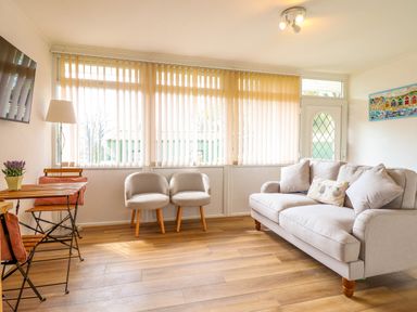 A sitting room with a sofa two chairs a small dining table and vertical blinds on the windows at Hill View in Bryncrug near Tywyn