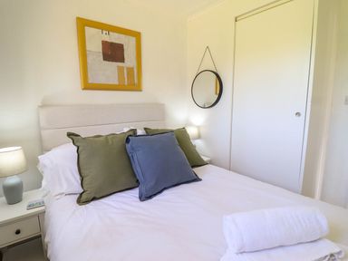 A bedroom with a bed with green and blue pillows and white towels on the bed at Hill View in Bryncrug near Tywyn