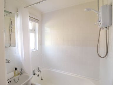 A bathroom with a bathtub shower sink and a window at Hill View Bryncrug near Tywyn