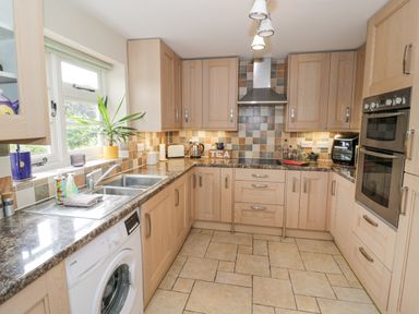 A kitchen with wooden cabinets brown countertops a double sink a washing machine and built in oven at Orchard View Redmary D Abitot near Hartpury