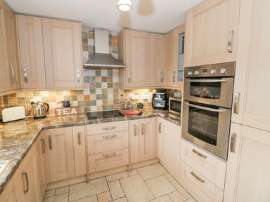 A kitchen with wooden cabinets stainless steel oven and tiled backsplash at Orchard View Redmary D'Abitot near Hartpury