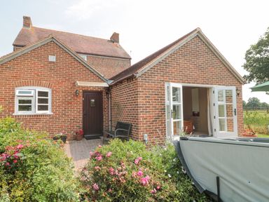 A brick house with a dark wooden door and white framed open double doors surrounded by flowers at Orchard View Redmary D Abitot near Hartpury