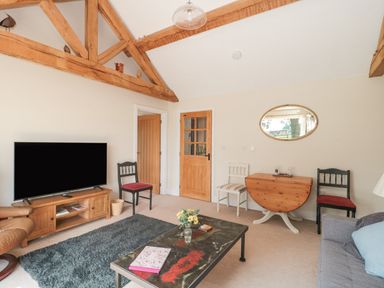 A living room with wooden beams a television on a stand chairs and a coffee table at Orchard View in Redmary D Abitot near Hartpury