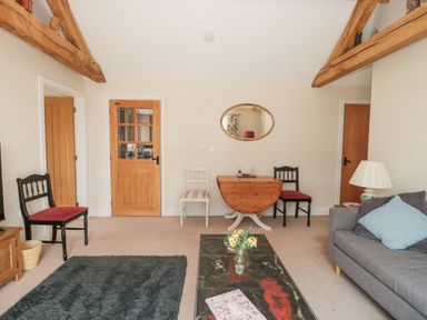 A living room with wooden beams on ceiling chairs and a table with mirror on wall at Orchard View Redmary D Abitot near Hartpury