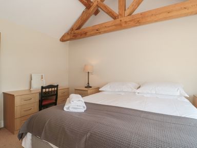 A bedroom with a bed towels on top a bedside table lamp and a desk with a chair at Orchard View in Redmary D Abitot near Hartpury