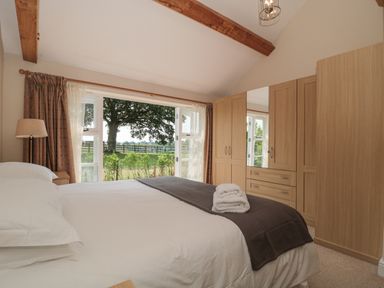 A bedroom with a bed linens and folded towels near wardrobes and a window showing a tree at Orchard View Redmary D Abitot near Hartpury