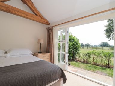 A bedroom with a bed lamp and open doors leading to a garden at Orchard View in Redmary D Abitot near Hartpury