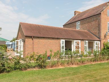 A brick building with open white-framed doors and a hedge in front at Orchard View in Redmary D Abitot near Hartpury