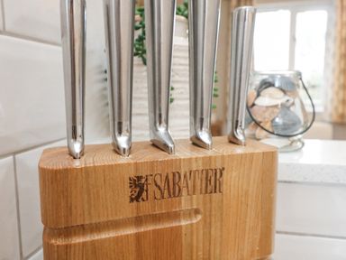 A wooden knife block with stainless steel knives in a kitchen at Breeze Cottage in Falmouth