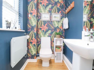 A bathroom with a toilet sink and floral wallpaper at Breeze Cottage in Falmouth