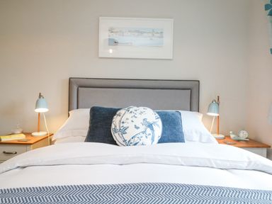 A bed with pillows and lamps on bedside tables at Breeze Cottage in Falmouth