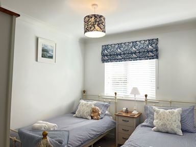 A bedroom with two beds and a nightstand at Breeze Cottage in Falmouth