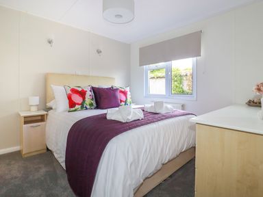 A bedroom with a double bed pillows and bedside table at Lowen Lodge in St Merryn near Padstow